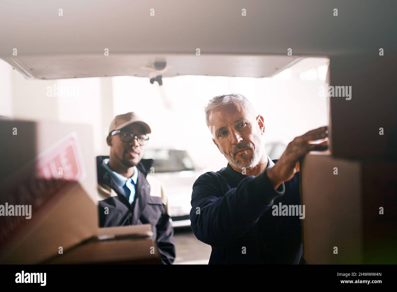 Caricare le merci con la massima cura. Shot di consegna uomini che caricano scatole in un veicolo. Foto Stock
