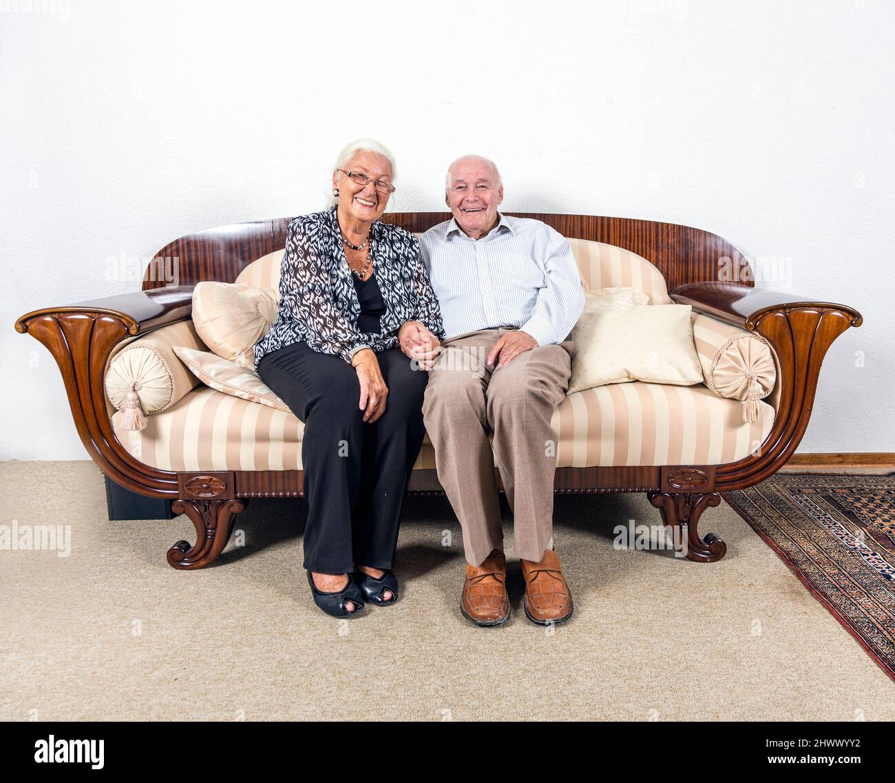 Caucasian coppia senior in amano sedersi su un divano Foto Stock