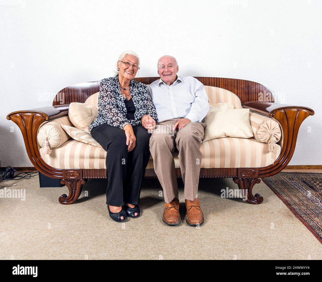 Caucasian coppia senior in amano sedersi su un divano Foto Stock