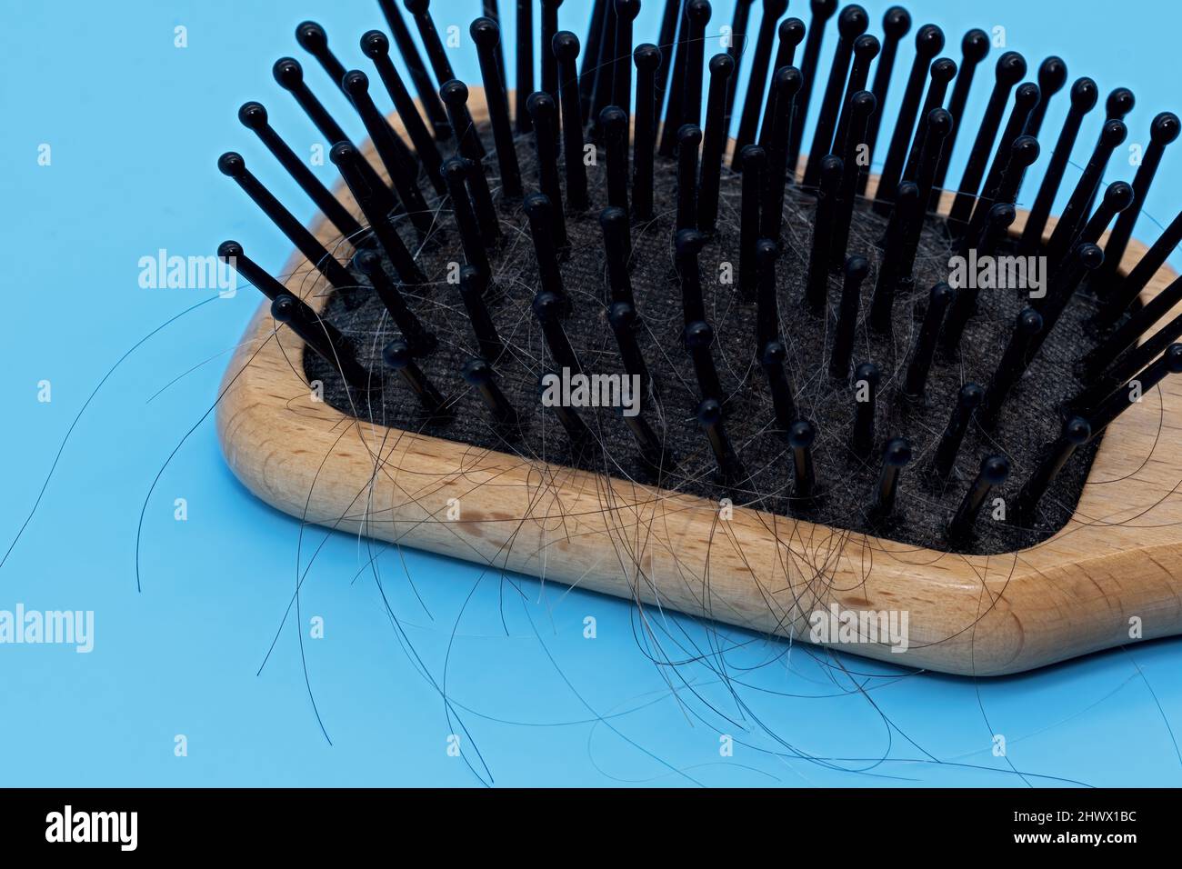 Spazzola in legno con denti in plastica e capelli neri e grigi caduti Foto Stock