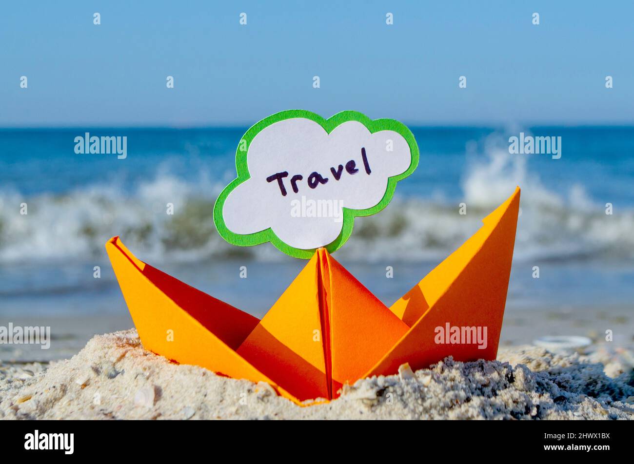 Orange Paper Boat su Sandy Seashore Close-up. Piccola barca da carta Foto Stock