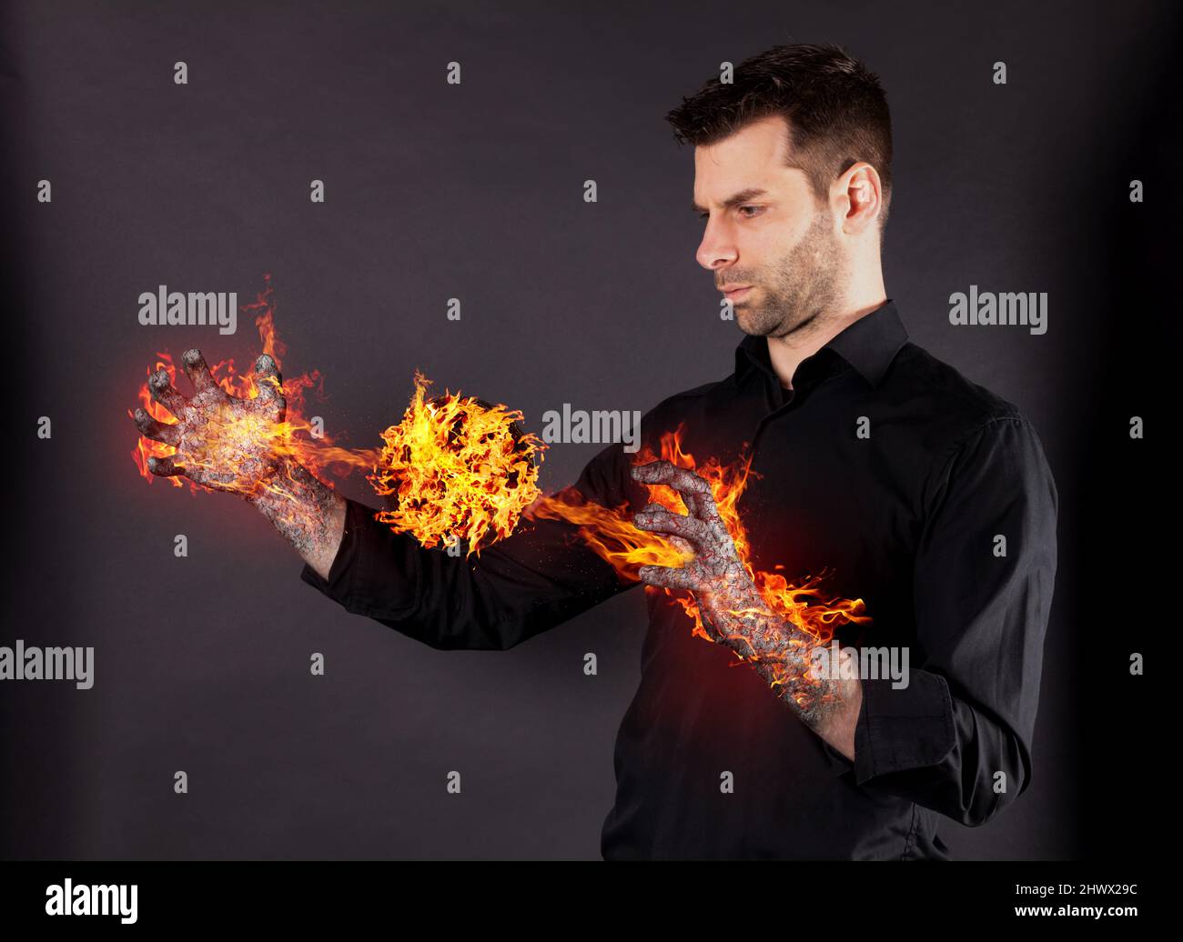 L'uomo che trasforma, brucia le mani, fa una sfera di fiamme che brucia - concetto di potere Foto Stock