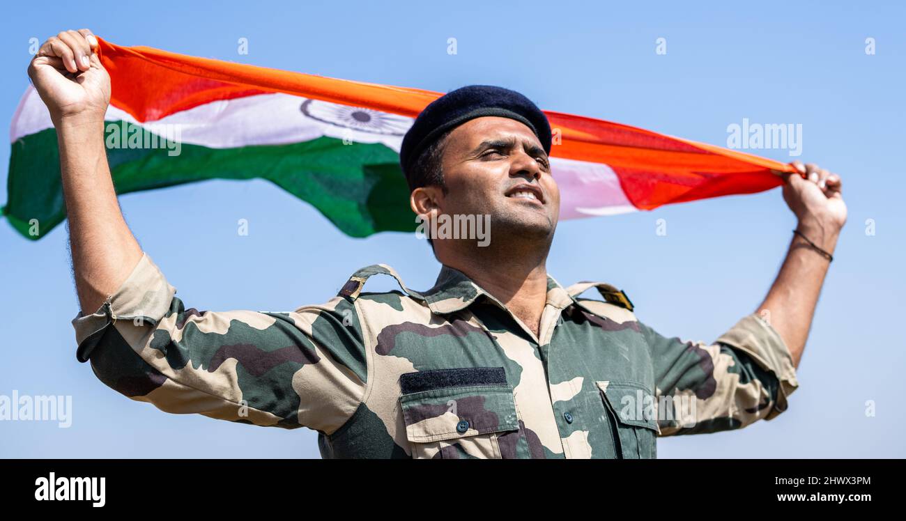 Esercito indiano soldato in mano che sventola bandiera indiana in uniforme - concetto di orgoglio nazionale, patriottismo, libertà e indipendenza Foto Stock