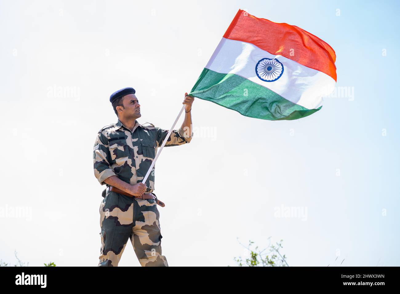 Esercito indiano soldato che tiene sventolare bandiera indiana sulla cima della montagna - concetto di indipendenza o festa del giorno del Repubblica, patriottismo e orgoglio Foto Stock