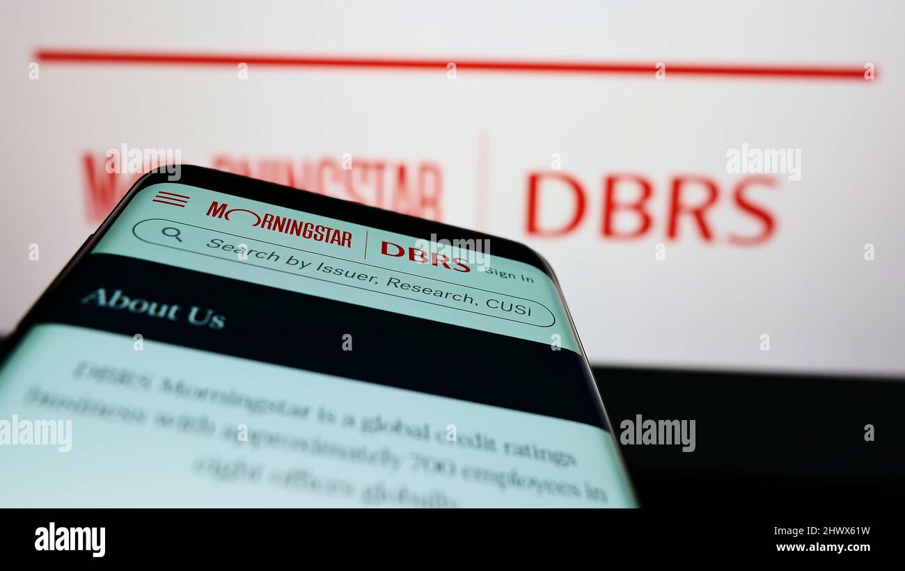Telefono cellulare con pagina web della società di rating canadese DBRS Morningstar sullo schermo di fronte al logo. Mettere a fuoco sulla parte superiore sinistra del display del telefono. Foto Stock