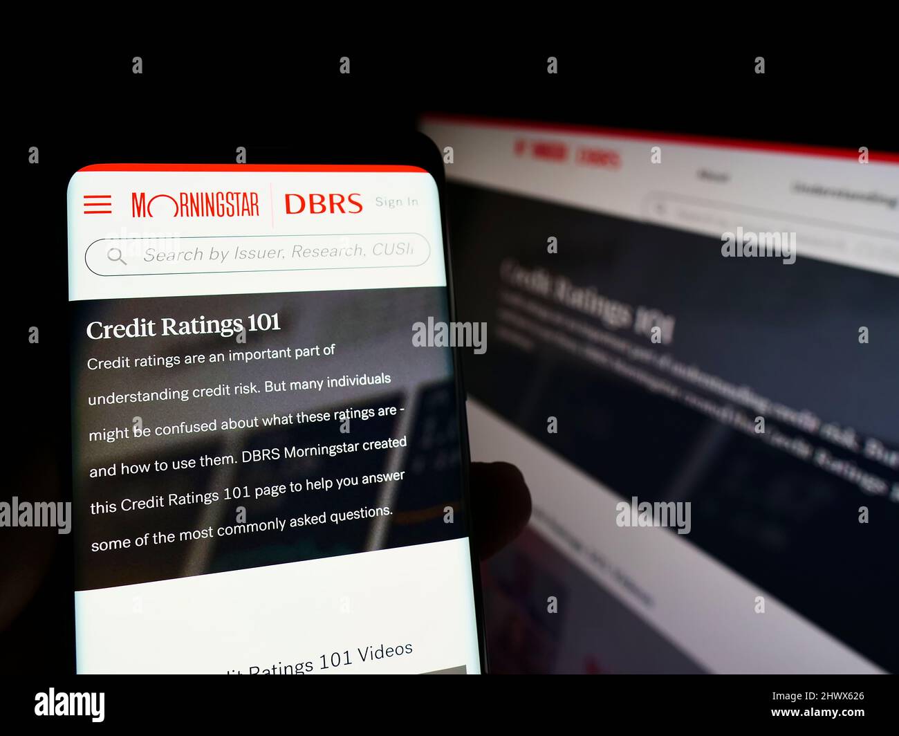 Persona che tiene smartphone con sito web della società di rating canadese DBRS Morningstar su schermo con monitor. Concentrarsi sul centro del display del telefono. Foto Stock