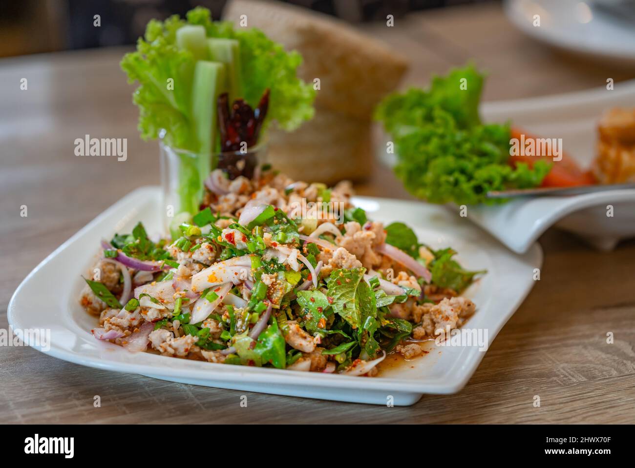 Primo piano Larb Moo o insalata di maiale speziata sminuzzata servita con verdure fresche, il tradizionale popolare cibo speziato thailandese del nord, Thailandia. Cibo in whit Foto Stock