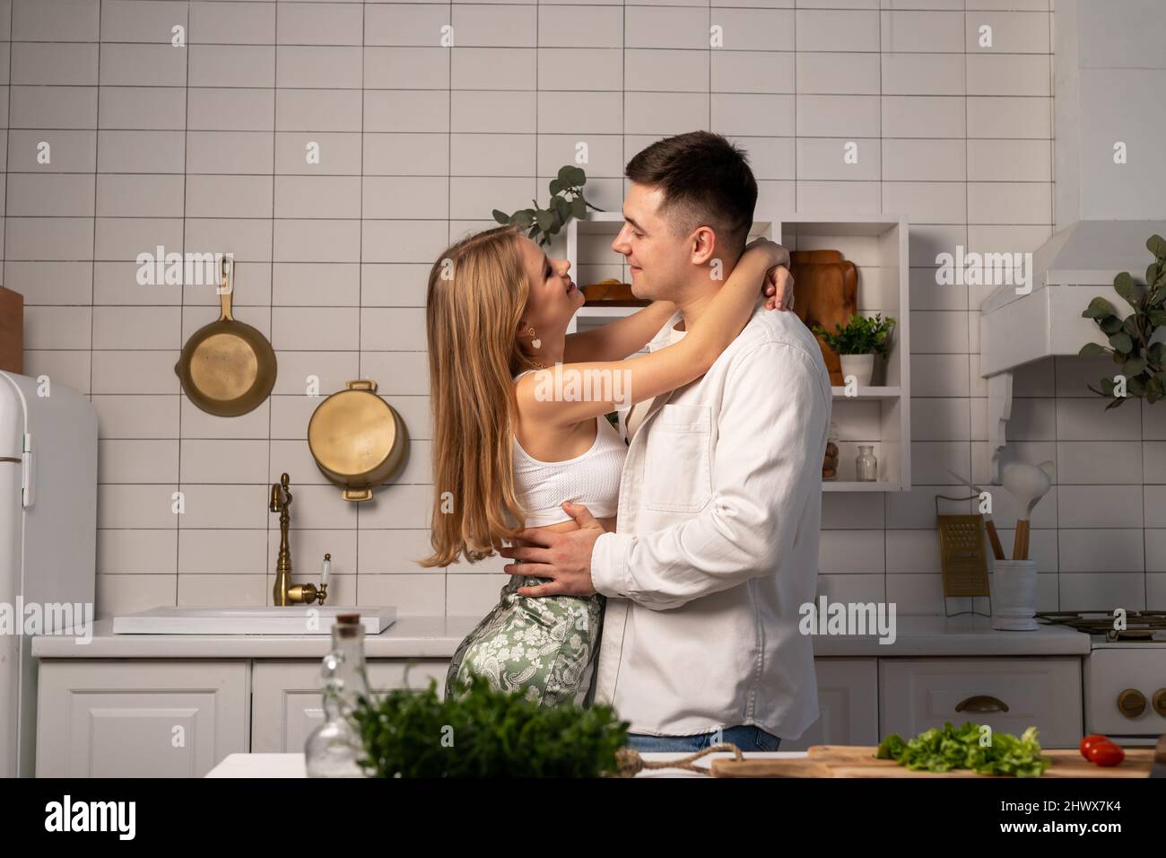 Felice giovane coppia abbraccia mentre cucinava a casa. Bell'uomo e bella donna sorridente. Relazione romantica e tenera. Foto di alta qualità Foto Stock