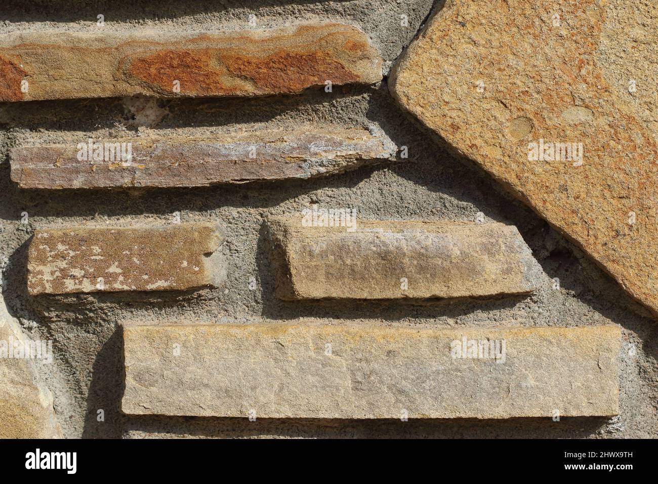 primo piano della struttura a parete del giardino in pietra. Primo piano di un muro rustico in pietra con piastrelle di ardesia irregolari e Malta testurizzata Foto Stock