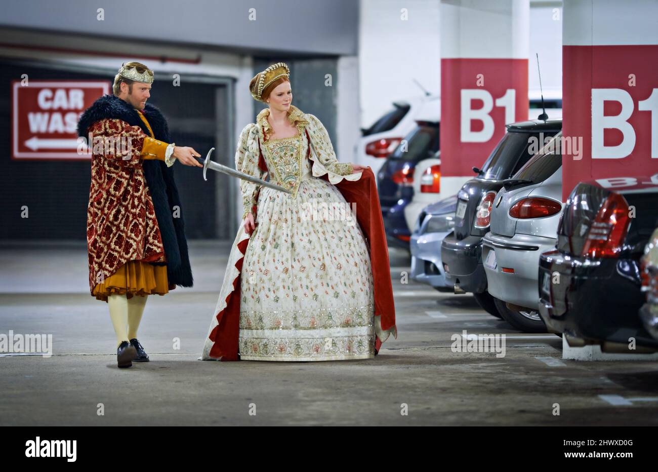 Rimettiti in piedi, ti occupiamo di queste creature. Un re e una regina in un garage parcheggio guardando le auto sospetto. Foto Stock