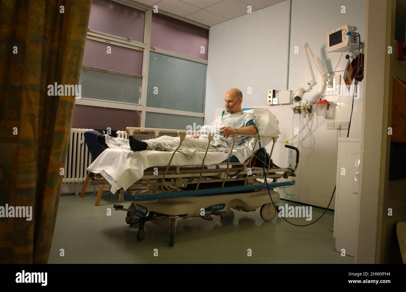 Un malato di attacco di cuore maschile si deposita nel suo letto con una riserva di ossigeno.(MODELLO RILASCIATO) Foto Stock