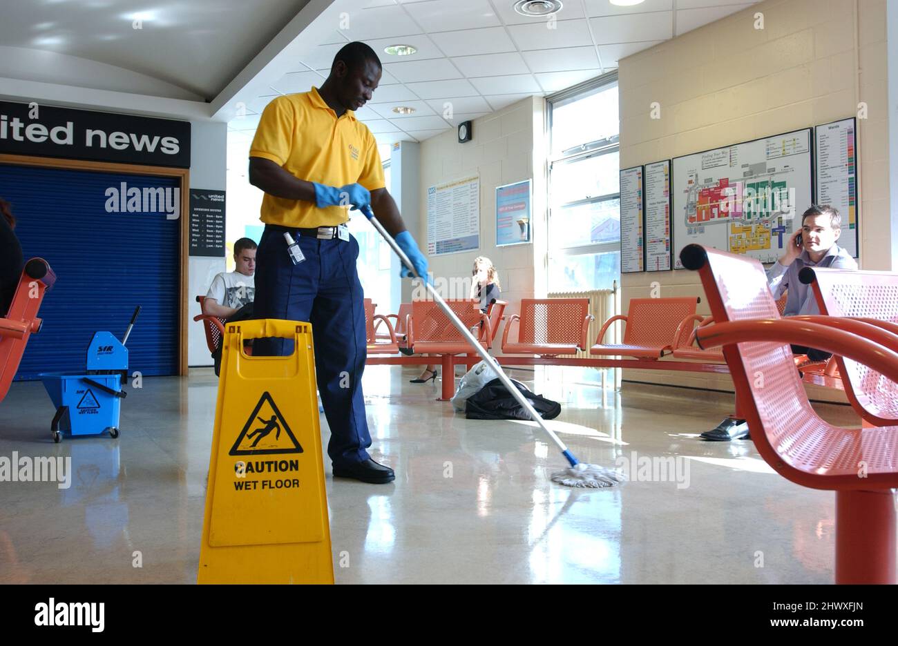 Un pulitore dell'ospedale, mopping il pavimento nell'area di ricezione dell'ospedale.(MODELLO RILASCIATO) Foto Stock