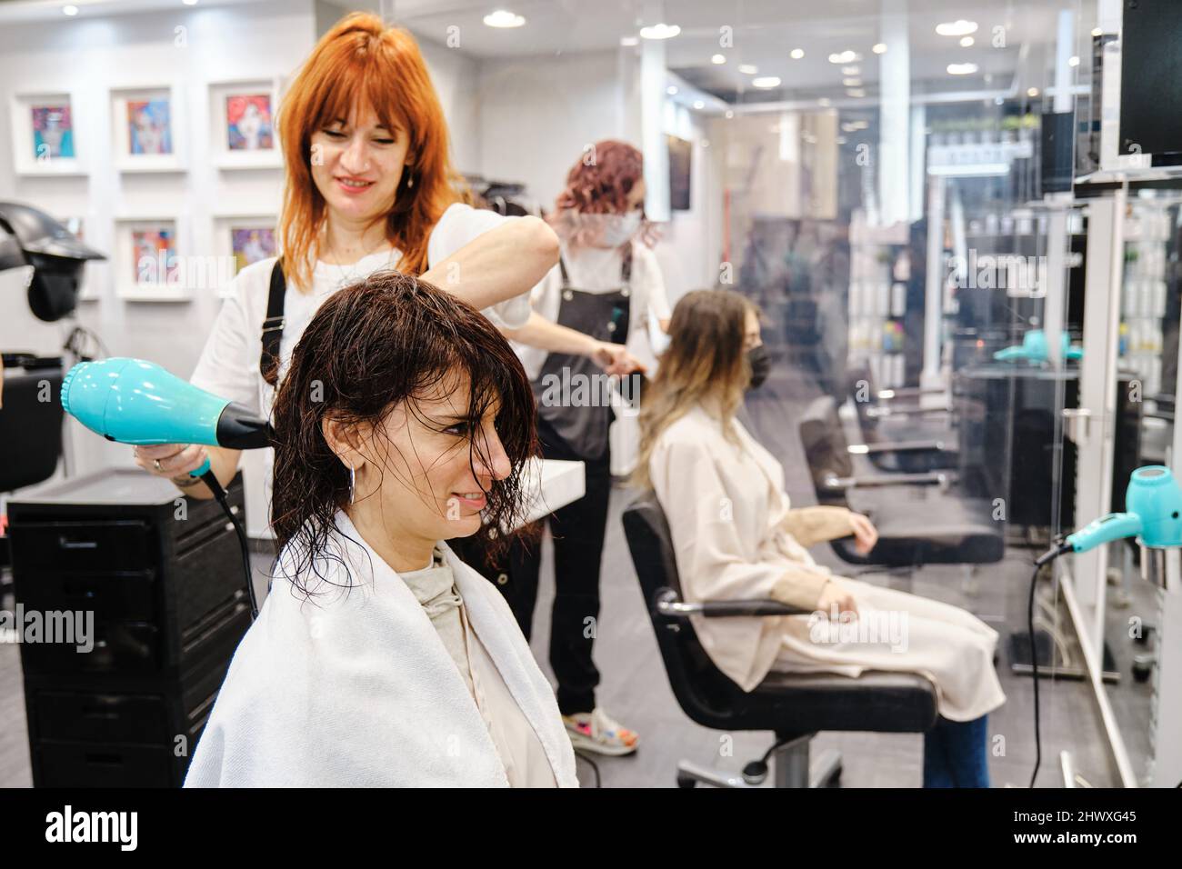 Il parrucchiere asciuga i capelli di un cliente dopo averli lavati nel salone di bellezza. Foto Stock