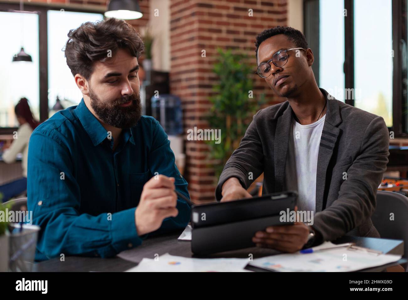 Diversi uomini d'affari che guardano il computer tablet che analizza le statistiche di marketing lavorando alla strategia aziendale in startup Office. Imprenditori multietnici che si occupano di idee di brainstorming per la collaborazione aziendale Foto Stock