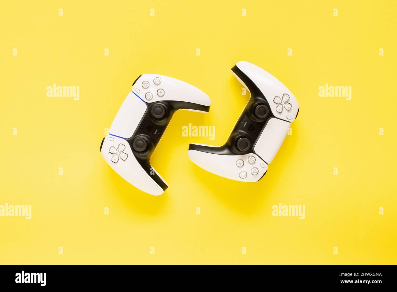 Ternopil, Ucraina - 05 marzo 2021: Due controller PlayStation 5 dualSense su sfondo giallo, concetto di gioco. Gamepad PS 5 Foto Stock