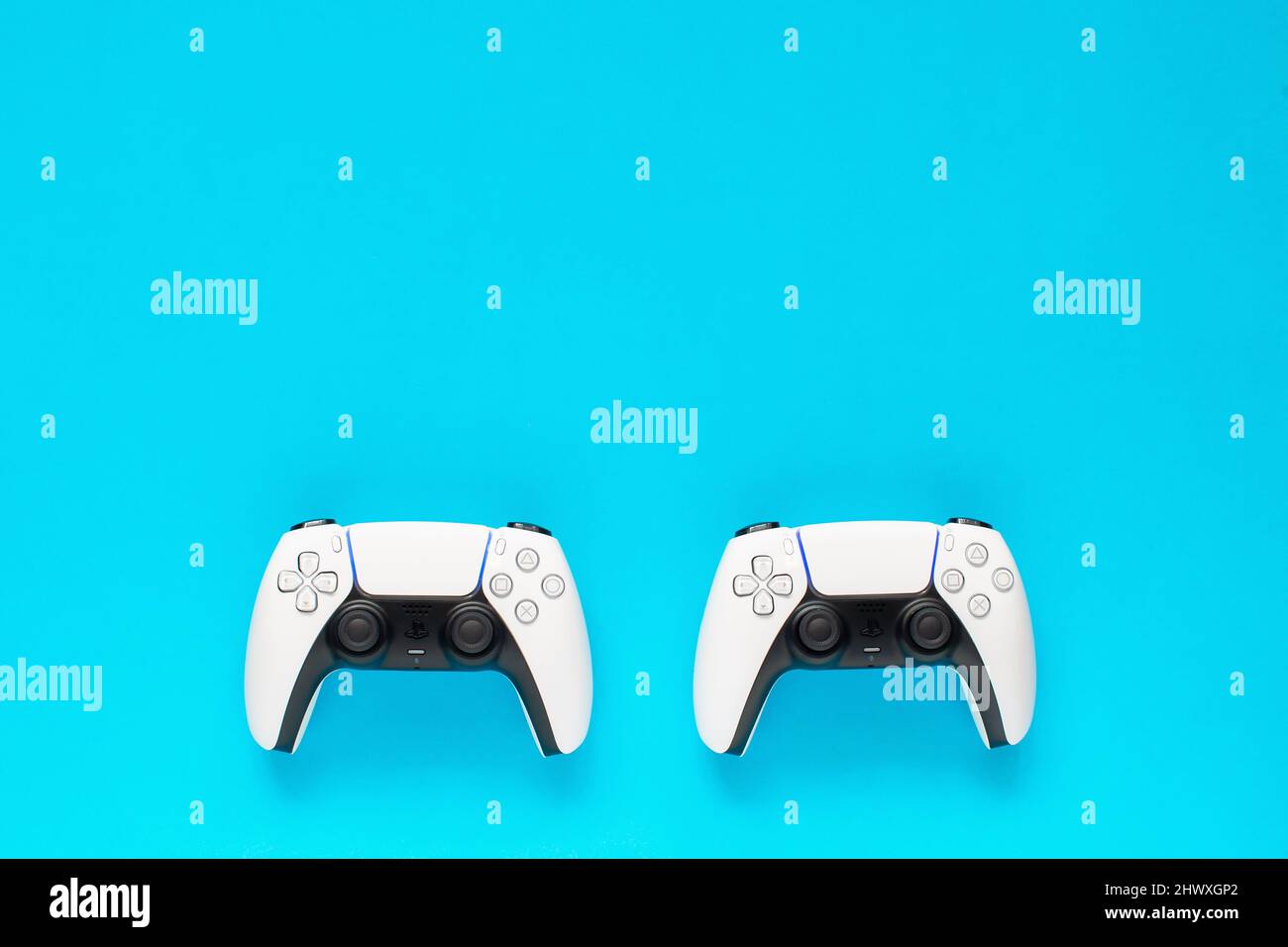 Ternopil, Ucraina - 05 marzo 2021: Due controller PlayStation 5 dualSense su sfondo blu, concetto di gioco. Gamepad PS 5 Foto Stock