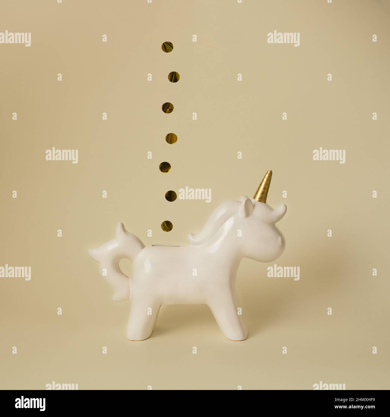 Bianco unicorno Piggy banca con monete d'oro su sfondo giallo minimo Foto Stock