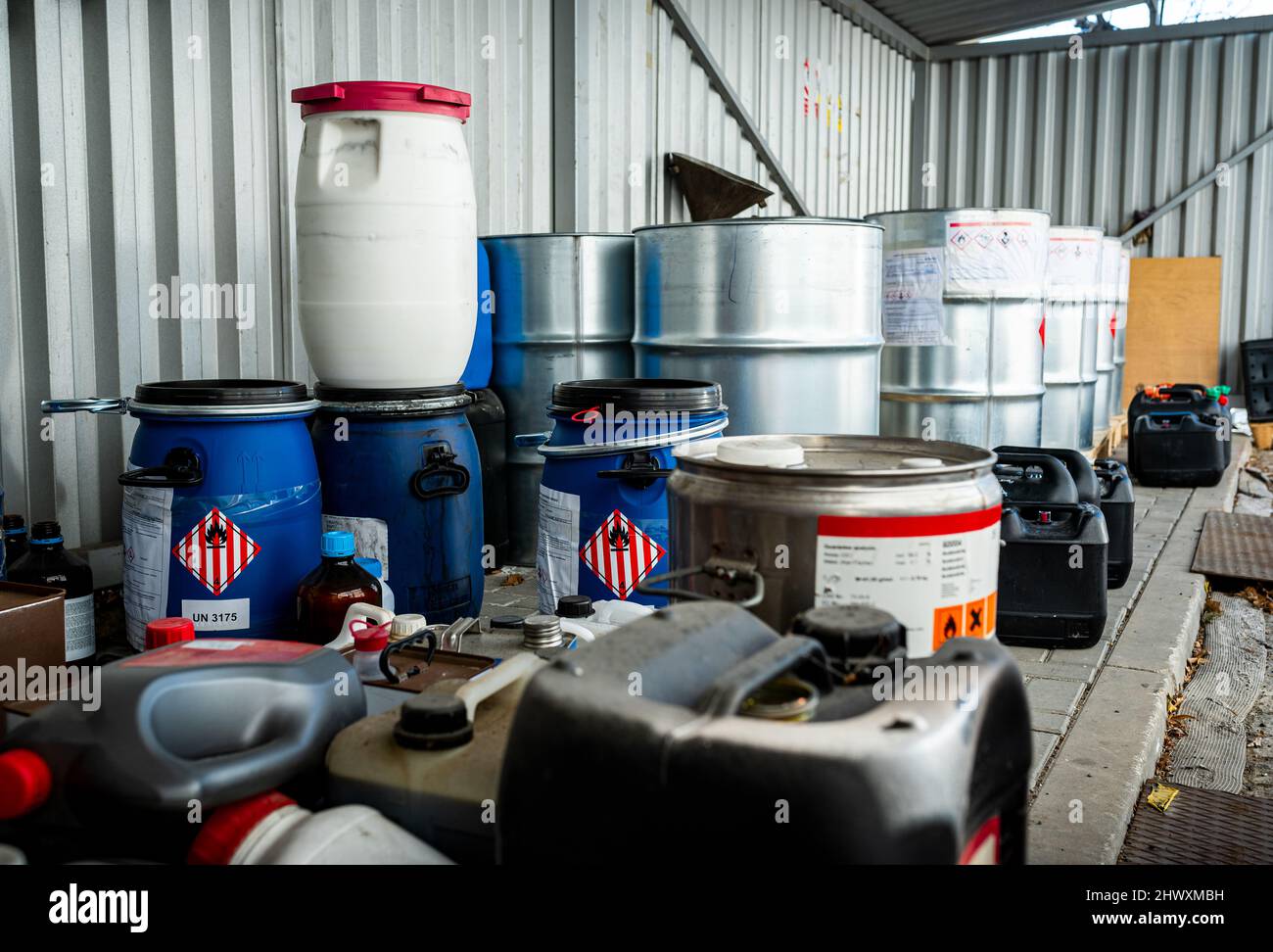 Barili in metallo e plastica contenenti sostanze chimiche pericolose dell'industria, concetto di gestione dei rifiuti Foto Stock