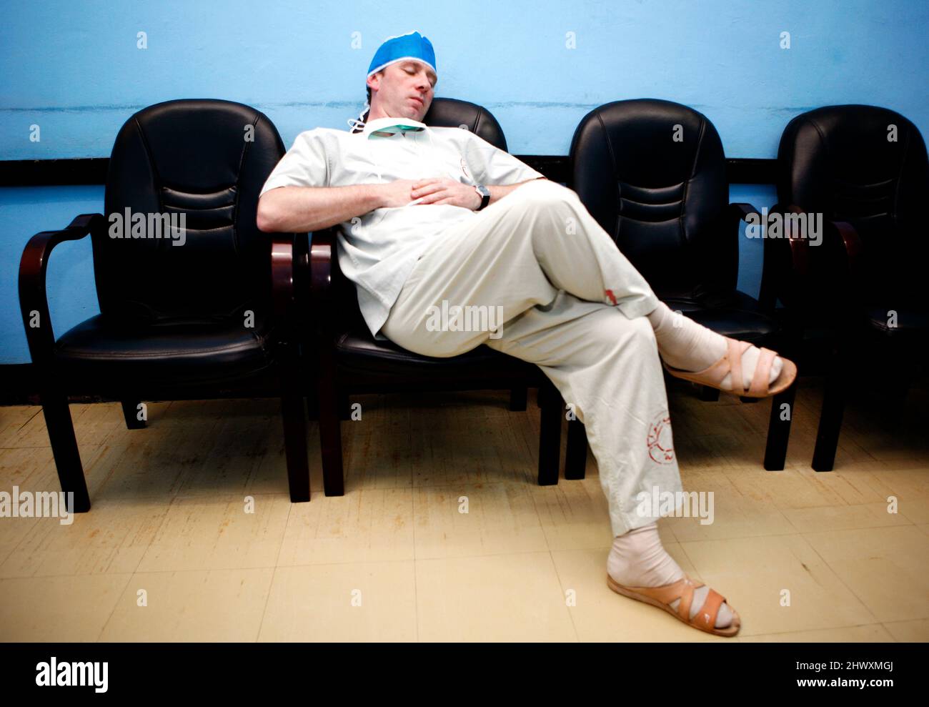 Un membro del personale del teatro dorme su una sedia nella sala d'attesa del personale dell'ospedale.(MODELLO RILASCIATO) Foto Stock