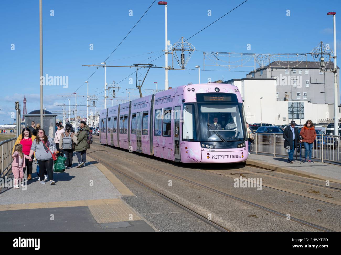 In una luminosa giornata di sole, un tram di colore rosa ferma a una stazione sul lungomare di Blackpool, Lancashire, Regno Unito Foto Stock
