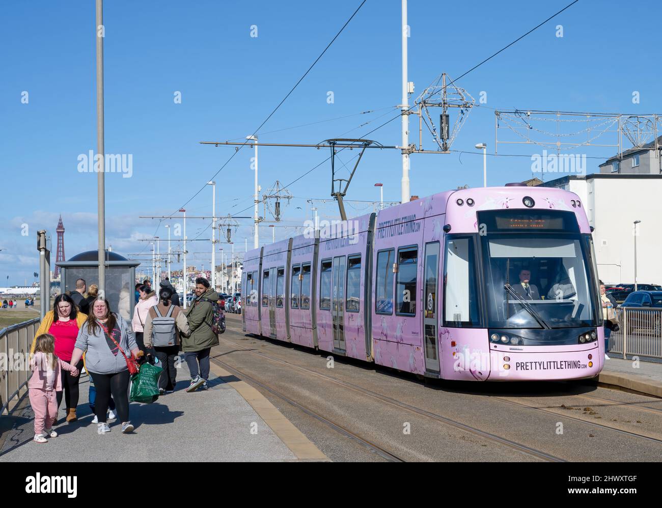 In una luminosa giornata di sole, un tram di colore rosa ferma a una stazione sul lungomare di Blackpool, Lancashire, Regno Unito Foto Stock