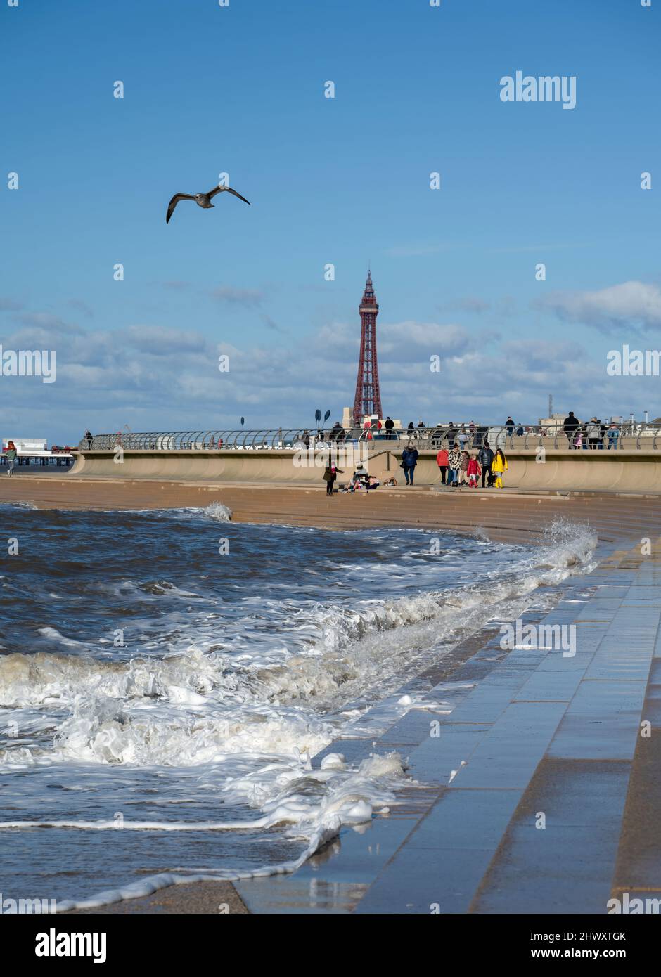 In una luminosa giornata di sole, i turisti hanno colpito la spiaggia sabbiosa sotto l'ombra della famosissima Blackpool Tower a Blackpool, Lancashire, Regno Unito Foto Stock
