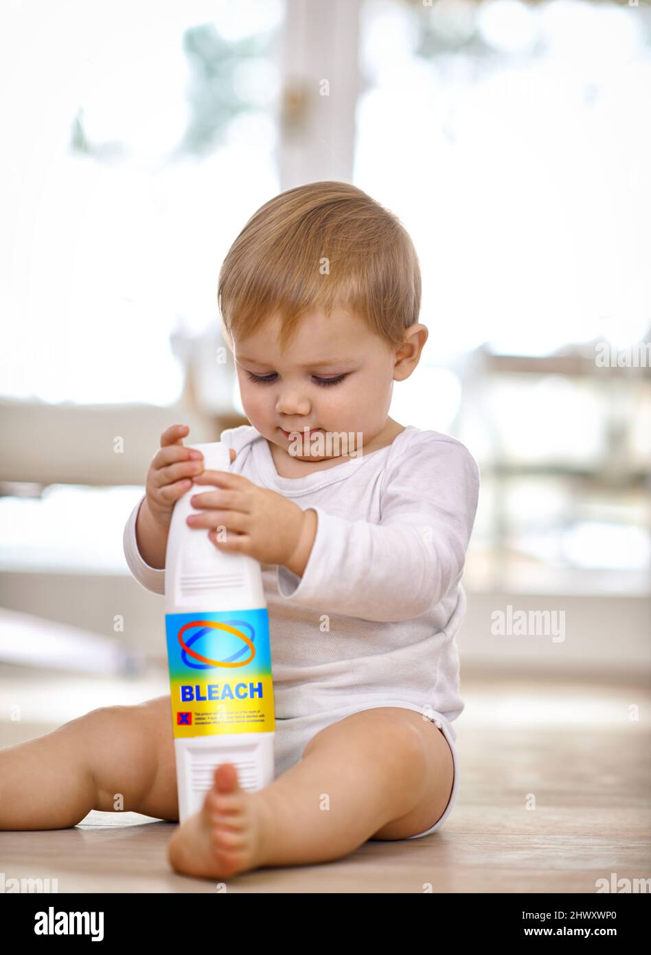 Tenere i bambini al sicuro - tenere gli oggetti nocivi fuori dalla portata. Shot di un bambino che gioca con un biberon con candeggina. Foto Stock