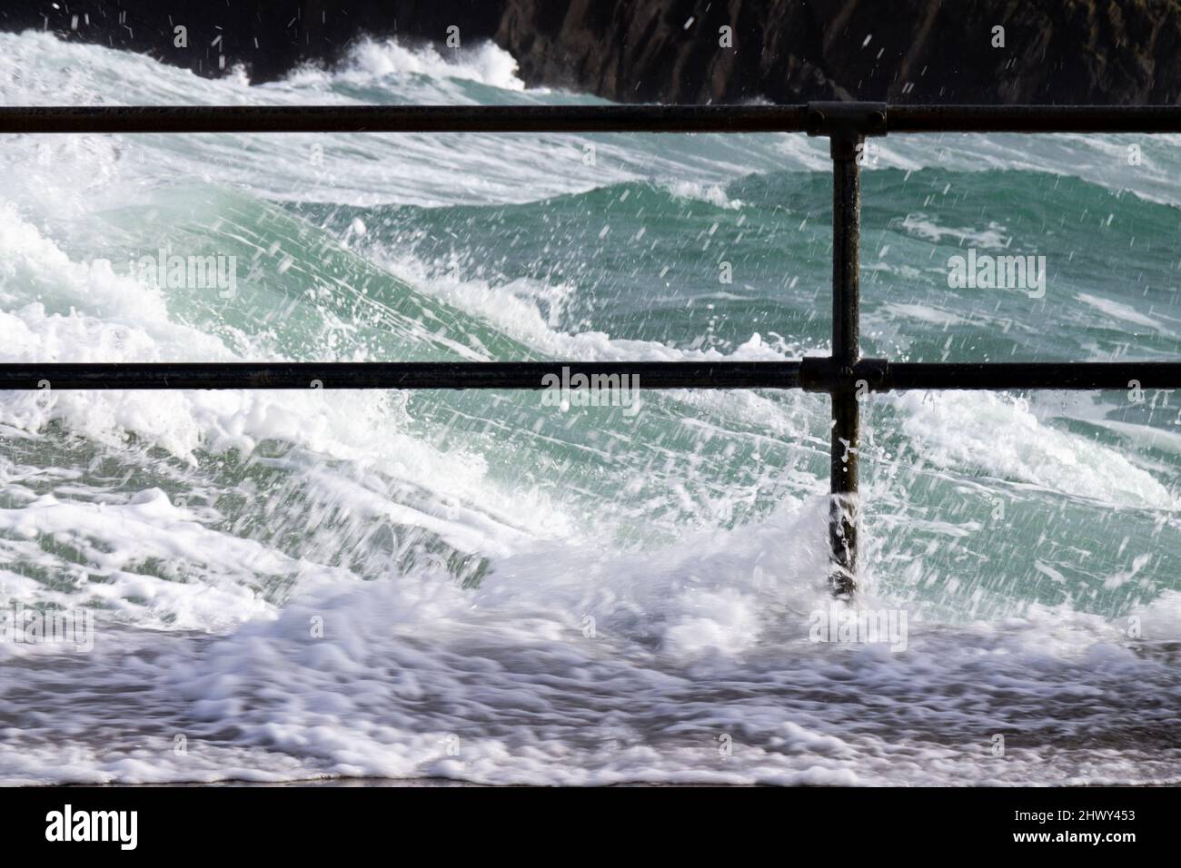 Le onde della tempesta invernale si infrangono sulla barriera di sicurezza del corrimano Rosscarbery Pier, West Cork, Irlanda Foto Stock