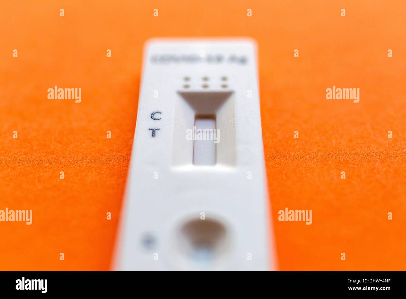 Risultato negativo del test utilizzando un dispositivo di test rapido per COVID-19 su sfondo arancione. Foto Stock