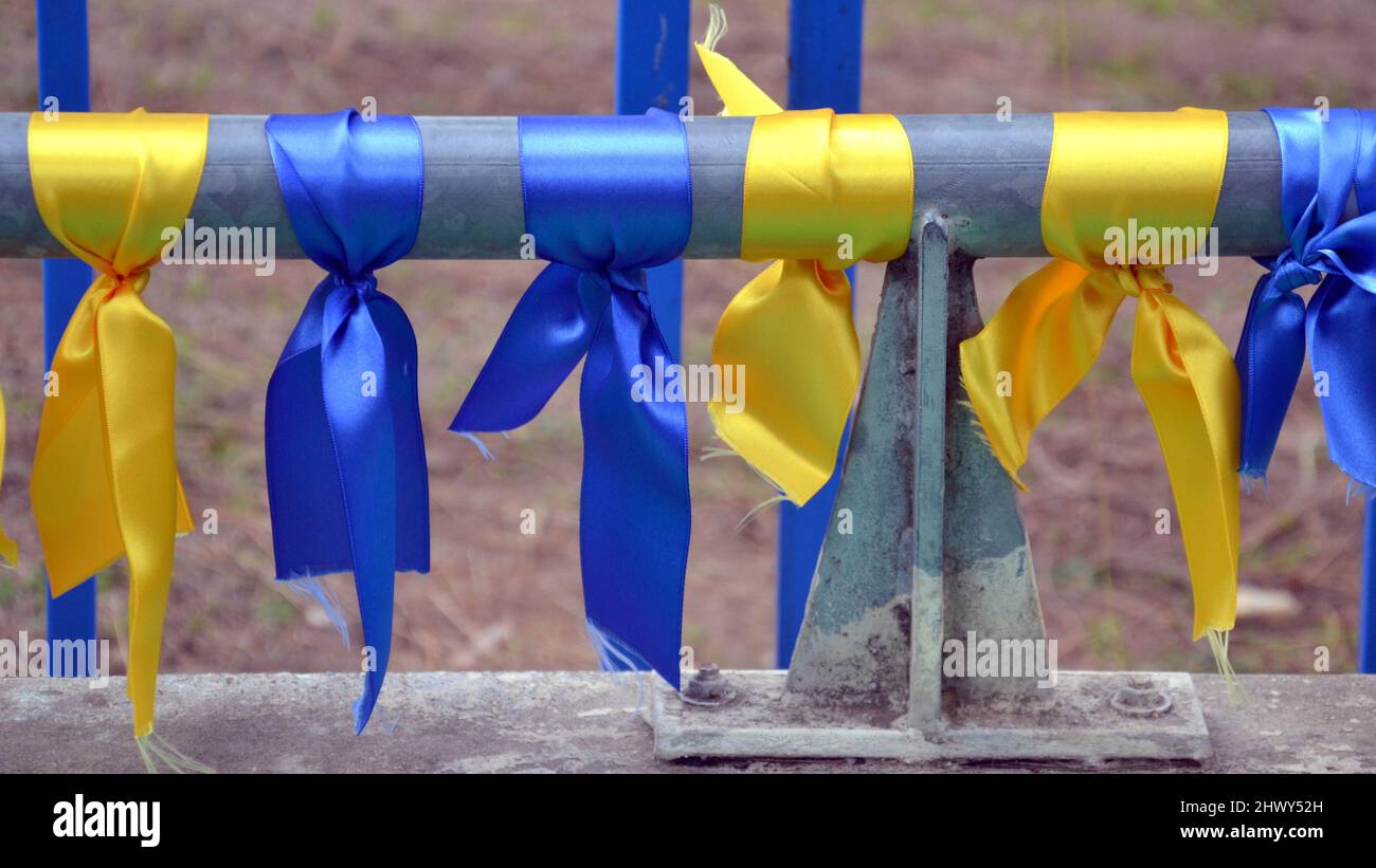 Nastri nei colori della bandiera Ucraina, blu e giallo, legati a un palo per protestare contro l'invasione russa e la guerra in Ucraina Foto Stock