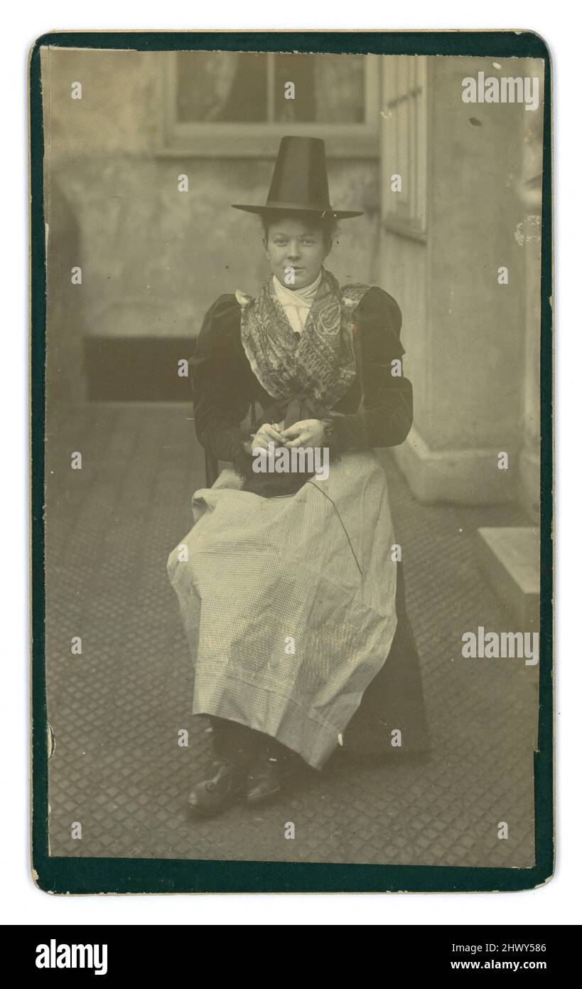 Victorian carte de Visite (CDV) o scheda di visita, di attraente giovane donna / ragazza più anziana, in costume gallese tradizionale, costume nazionale gallese, originariamente indossato da donne rurali, Ma alla fine del 19th secolo fu indossata per occasioni speciali come il festival di Eisteddfod (Eisteddfodau), cori e visite reali, che tiene in mano aghi e filati comuni in molte di queste foto. La ragazza indossa una scialle, un cappello nero alto e un abito o 'abito da letto'. Circa 1897, Galles, Regno Unito Foto Stock