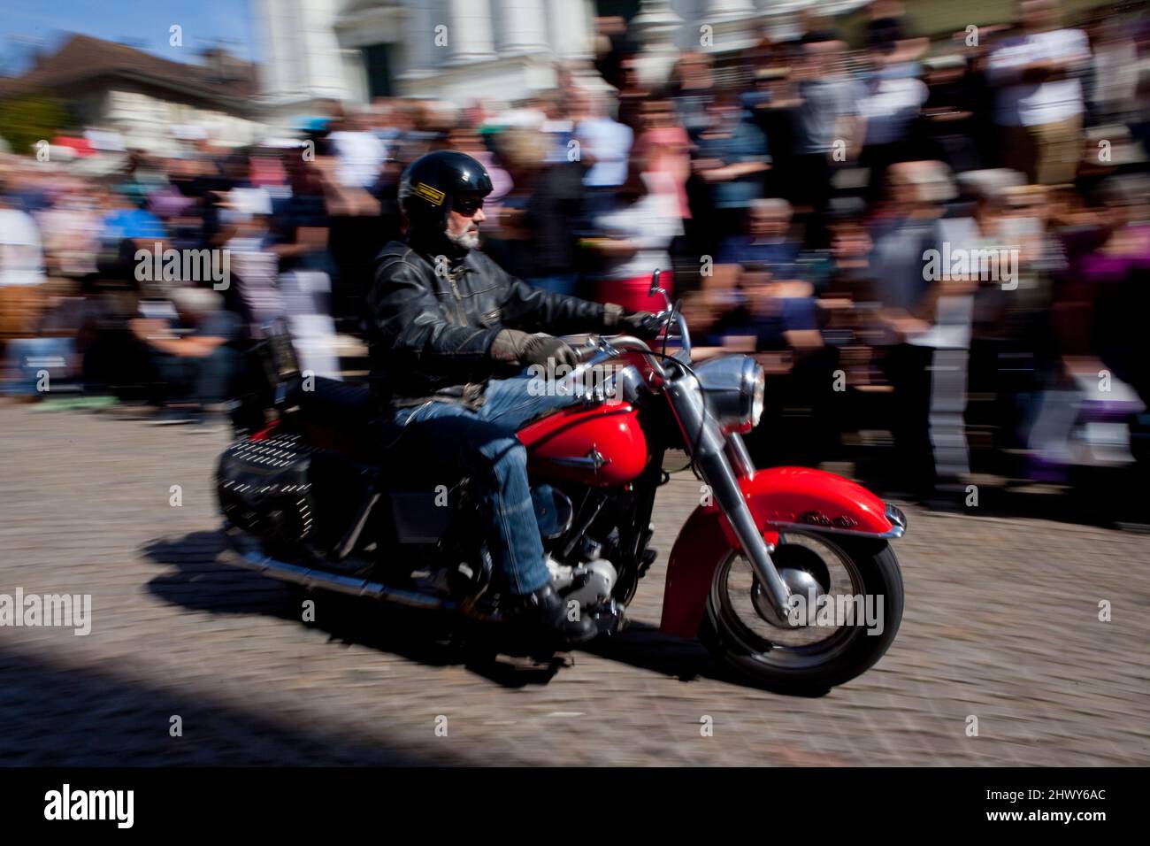 Un motociclista passa da una folla allegra durante una sfilata a Solothurn, in Svizzera. Foto Stock