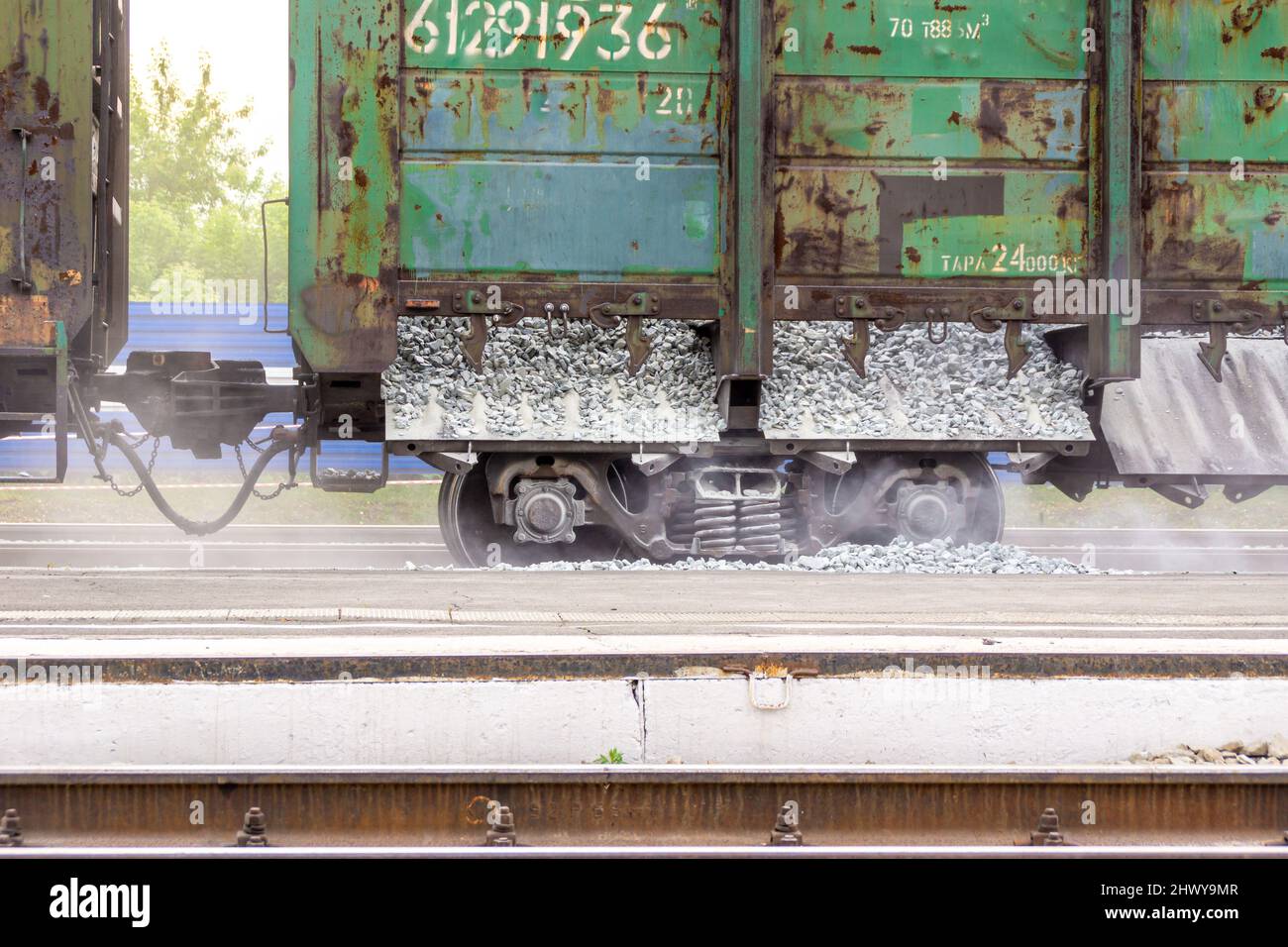 un paio di diversi vagoni di trasporto ferroviario non verniciati progettati per il carico alla rinfusa stanno completando lo scarico di macerie che si trova lungo la ferrovia, selectiv Foto Stock