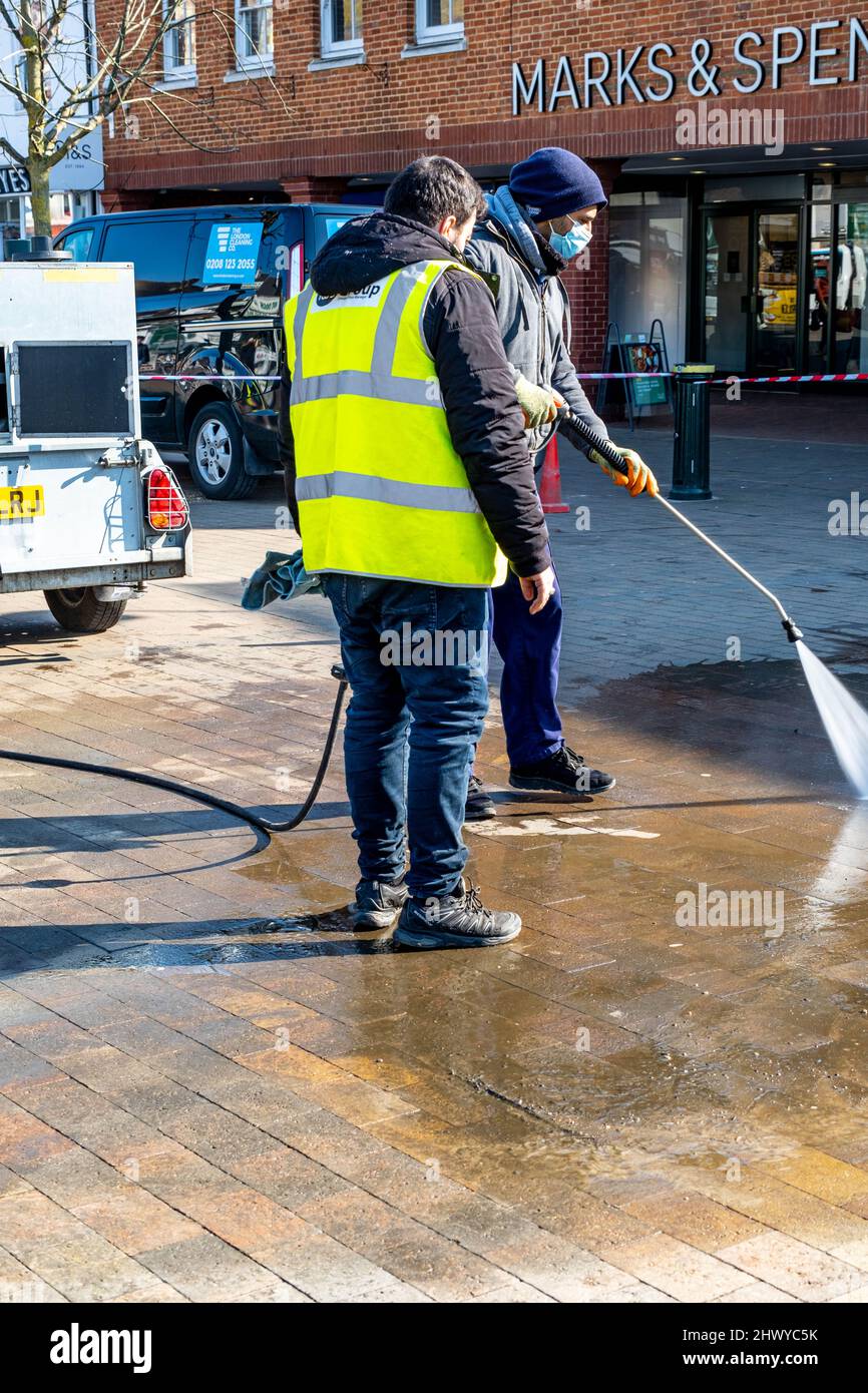 Epsom Surrey London UK, marzo 8 2022, due lavoratori edili pressione pulizia Di Un blocco Tile Paving Area fuori Marks e Spencer Foto Stock