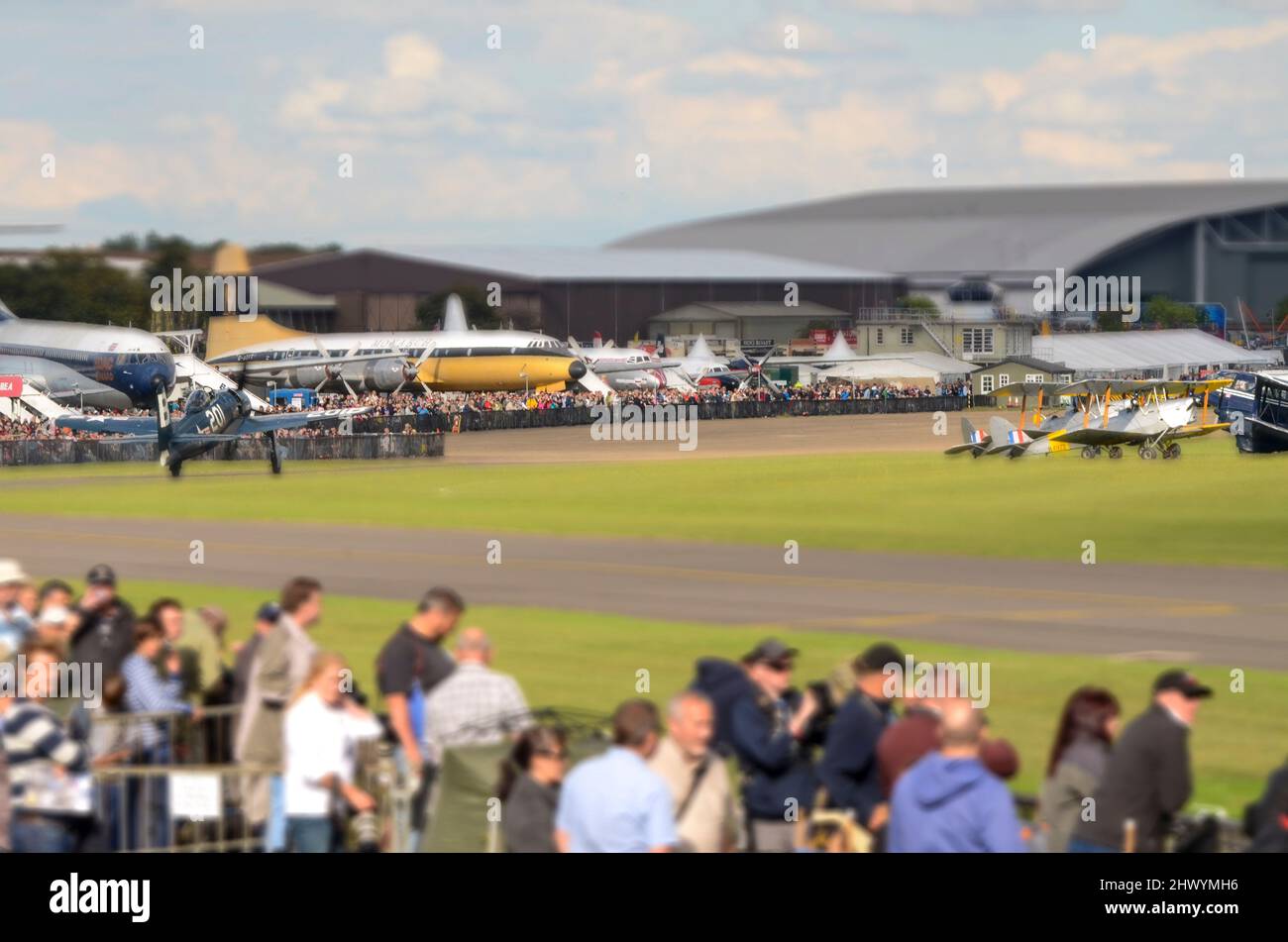 Aereo da caccia della seconda Guerra Mondiale che passa davanti alla folla all'IWM Duxford durante un'esposizione aerea. Manipolato dalla modalità di spostamento inclinazione della fotocamera su Nikon D7000 Foto Stock