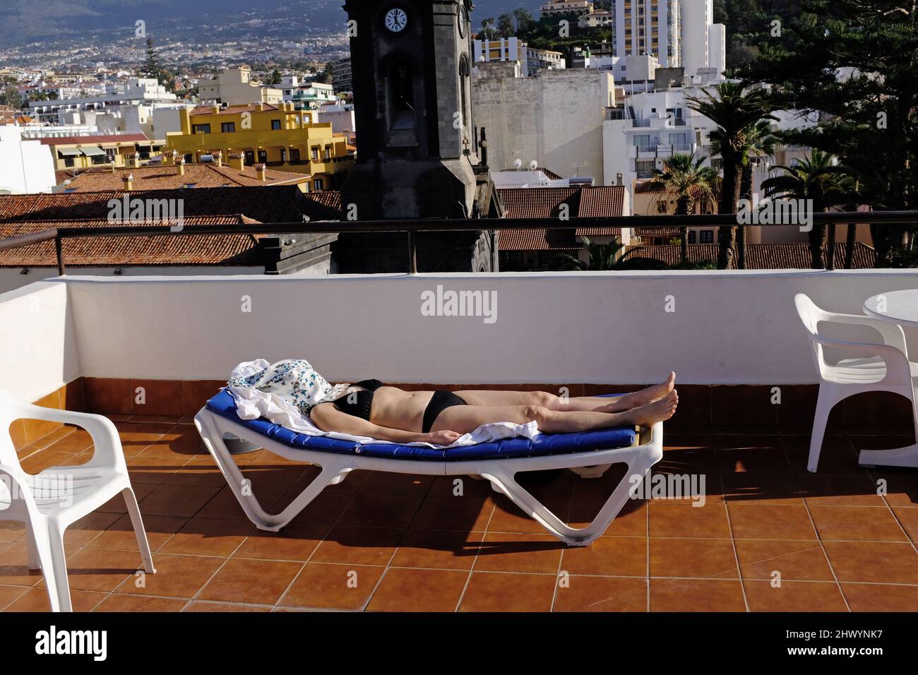 Una donna dorme su un sottiletto con una copertura per il viso per proteggersi dal sole. Foto Stock