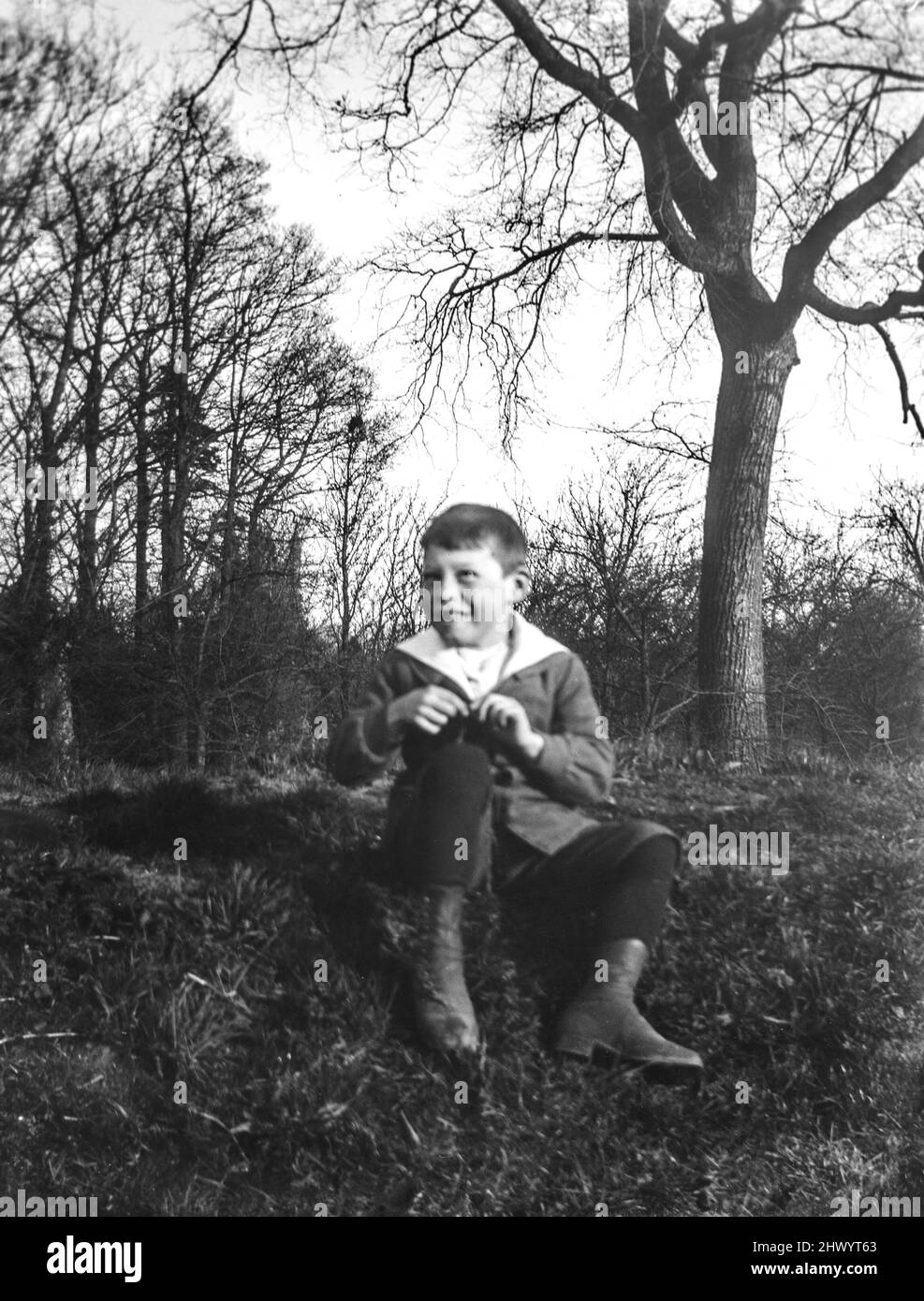 Ritratto informale edoardiano di un ragazzo seduto su una sponda di vetro. Tratto da una lastra di vetro d'epoca negativa. C1900 – 1910 Foto Stock