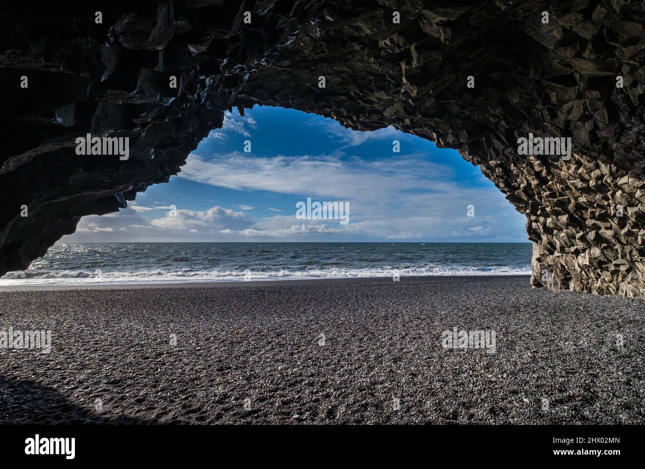 Vista sulla spiaggia di sabbia nera dell'oceano di Reynisfjara dalla grotta ai piedi del monte Reynisfjall. Colonne di roccia basaltica. Vik, Islanda del Sud. geol unico Foto Stock