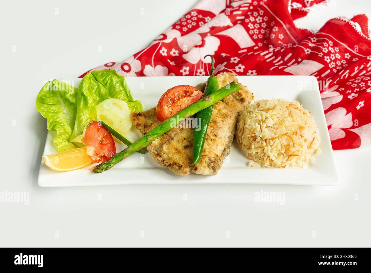 Spigola alla griglia con riso e insalata greca in un piatto isolato su colorato tavolo panno vista dall'alto su sfondo grigio Foto Stock