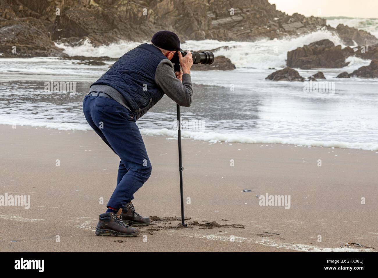 Uomo anziano che fotografa le onde della tempesta, St. Finian's Bay, County Kerry, Irlanda Foto Stock