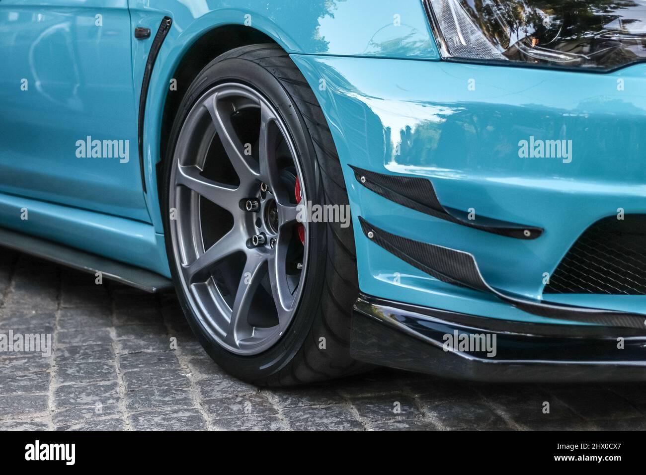 Primo piano di una ruota di un'auto sportiva. Cerchio grigio per auto con gomma a profilo basso. Auto sportiva blu. Foto Stock