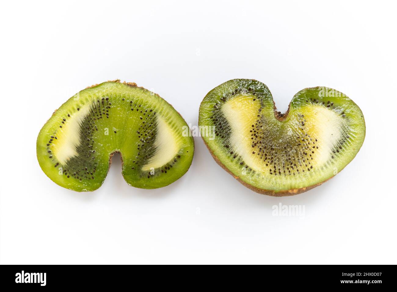 Immagine piatta di due metà di un kiwi con forma a cuore su pancipresso bianco orizzontale posizione opposta Foto Stock