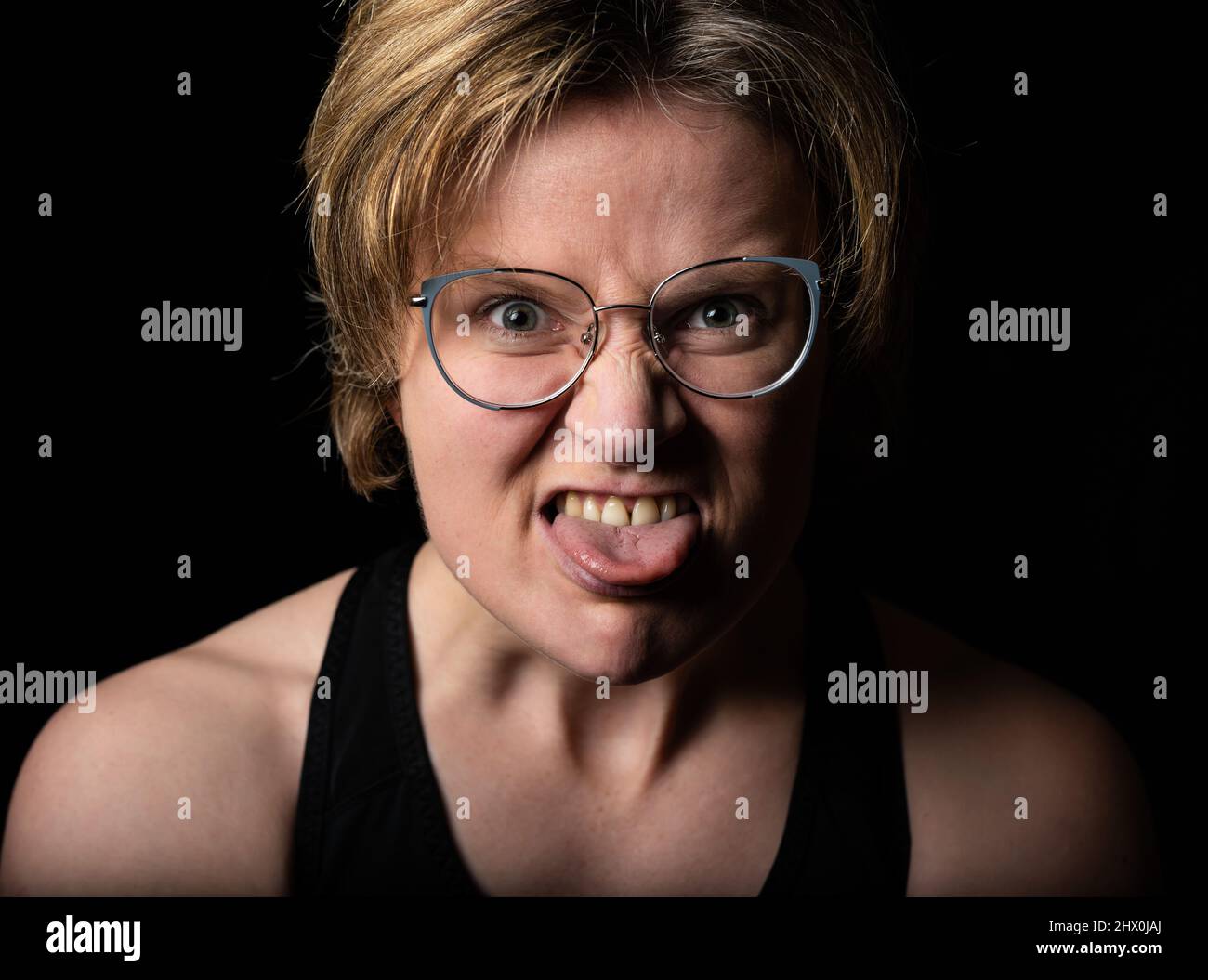 Basso ritratto di studio chiave di una donna bianca di 35 anni che tira la lingua, Bruxelles Foto Stock