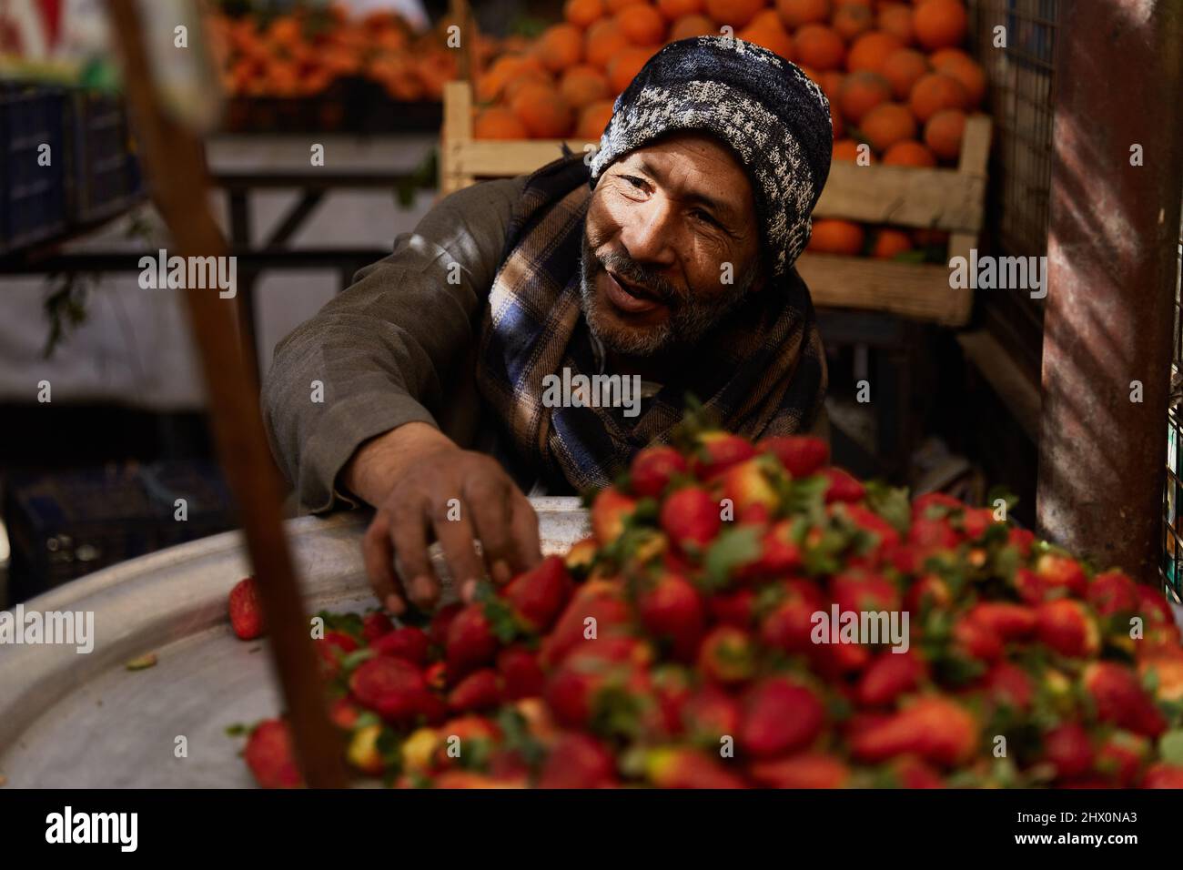 HURGHADA, EGITTO - 20 FEBBRAIO 2022: Venditore locale seduto nel mercato. Frutta fresca nel bazaar di strada Foto Stock