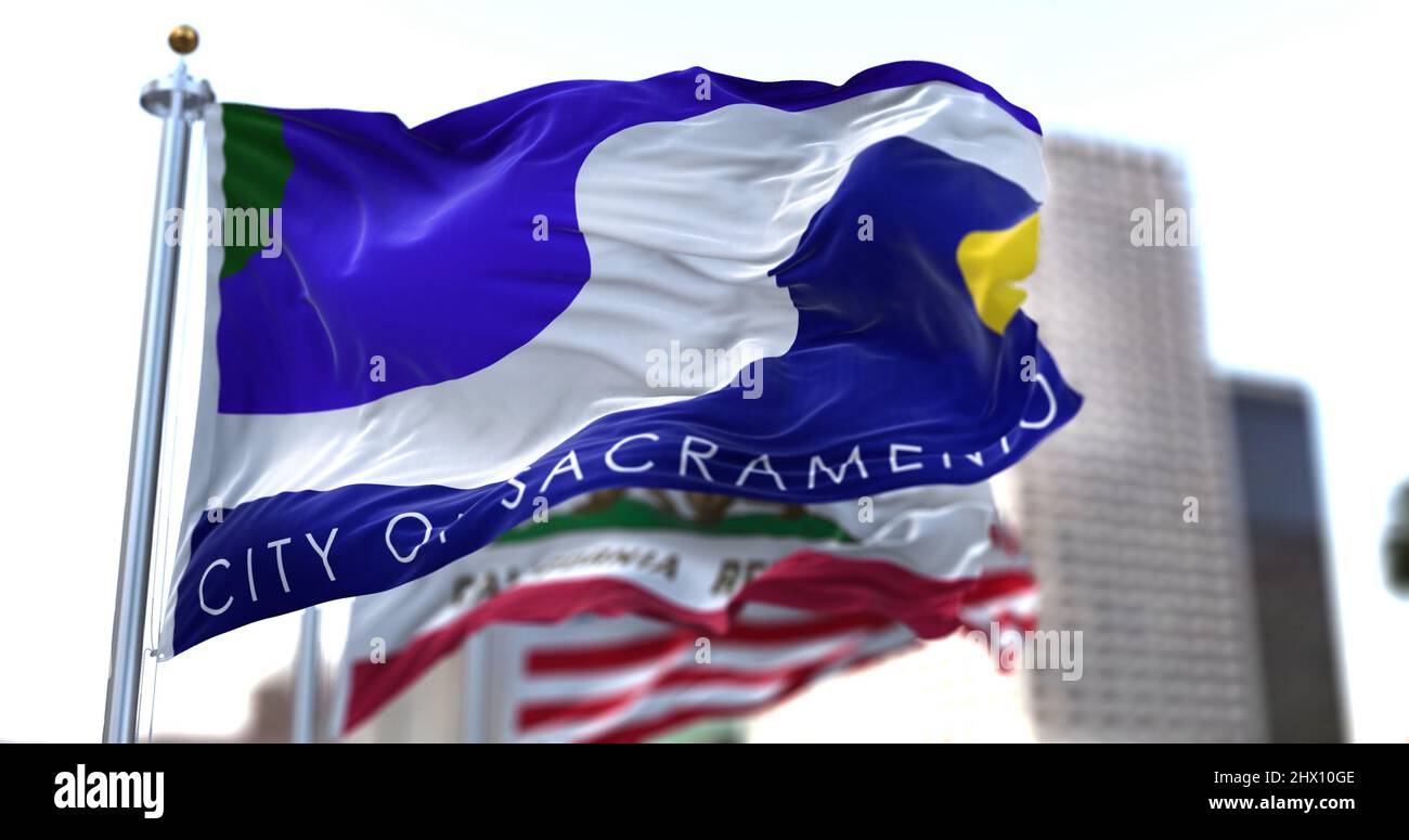La bandiera della città di Sacramento sventola nel vento con lo stato della California e le bandiere nazionali degli Stati Uniti sfocate sullo sfondo. Bandiera comunale di Sacramento Foto Stock