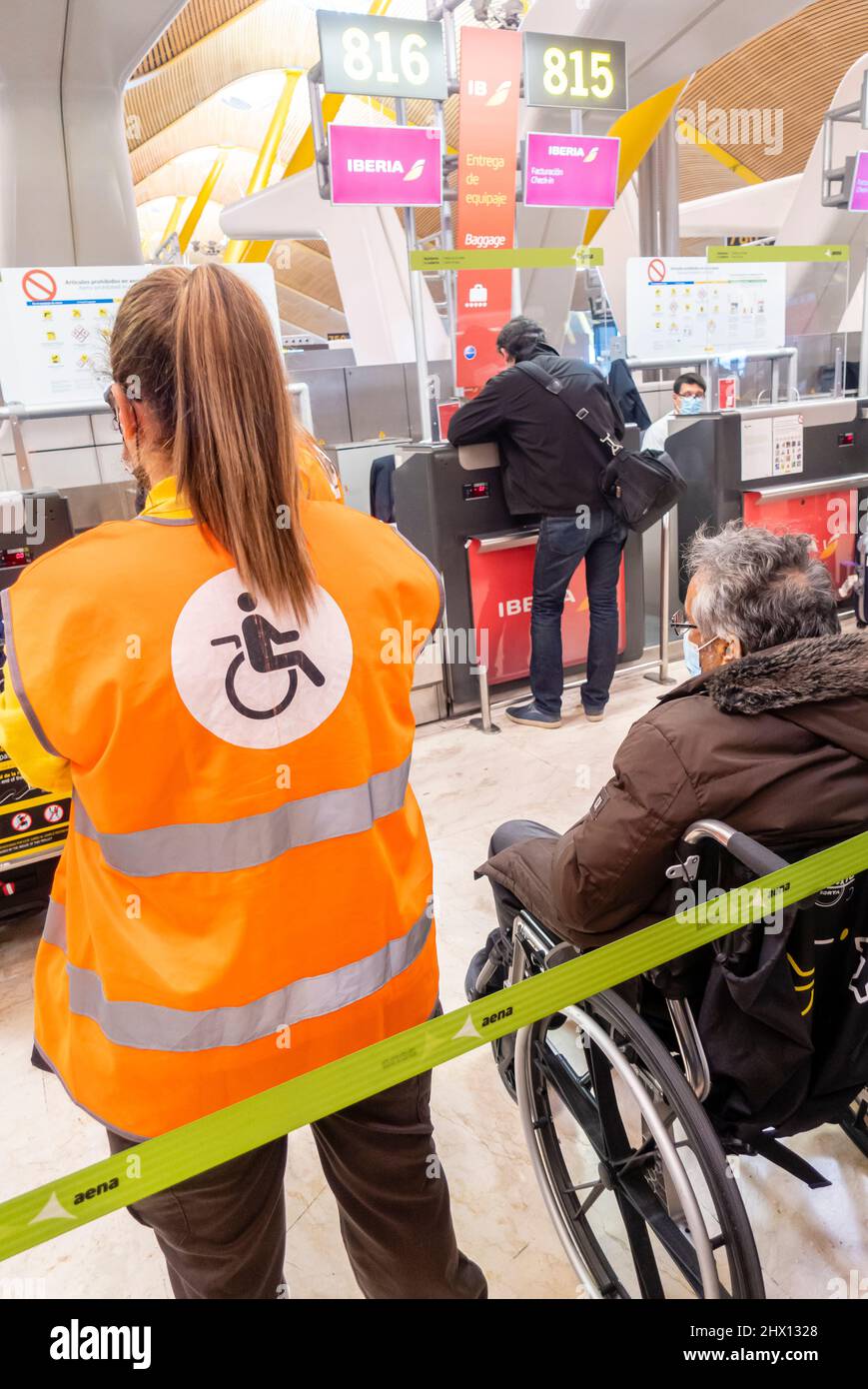 Membro dello staff dell'aeroporto che aiuta a prendersi cura di una donna anziana in sedia a rotelle per aiutare il suo check-in, aeroporto Madrid-Barajas, Spagna Foto Stock