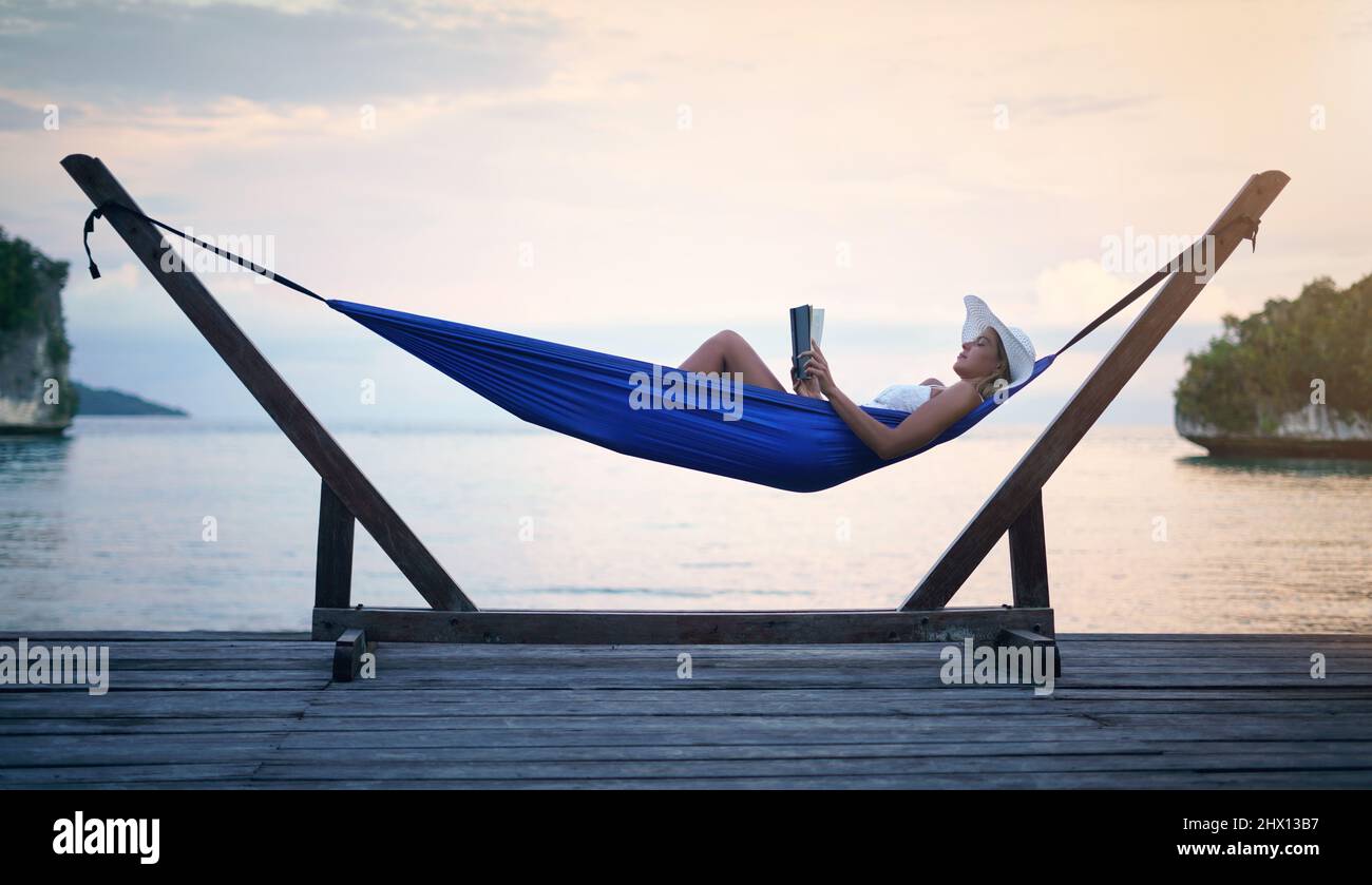 Shh, im in modalità vacanza. Scatto completo di una giovane donna attraente  seduta da sola in un'amaca e lettura di un libro durante una vacanza Foto  stock - Alamy