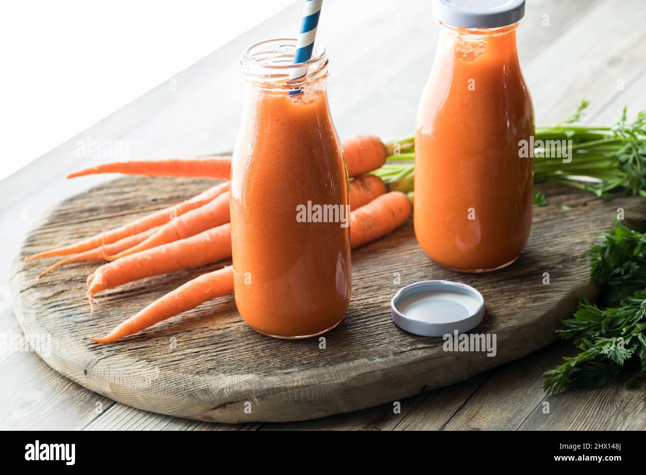 Bottiglie di sano succo di carota con luce brillante proveniente da dietro. Foto Stock