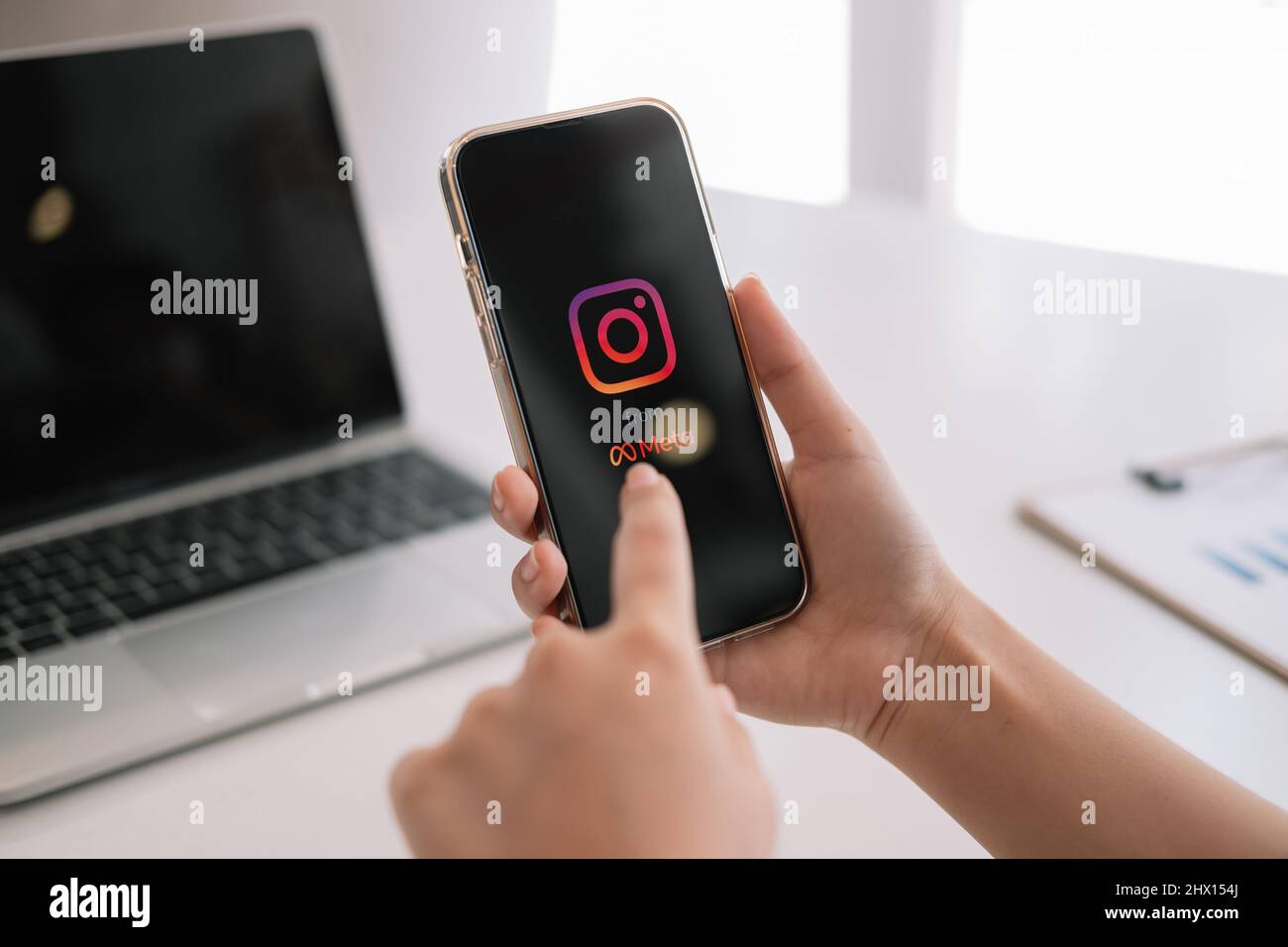 CHIANG mai, THAILANDIA - MAR 06 2022: Una donna tiene Apple iPhone 13 con l'applicazione Instagram da meta sullo schermo al caffè. Instagram è una foto Foto Stock