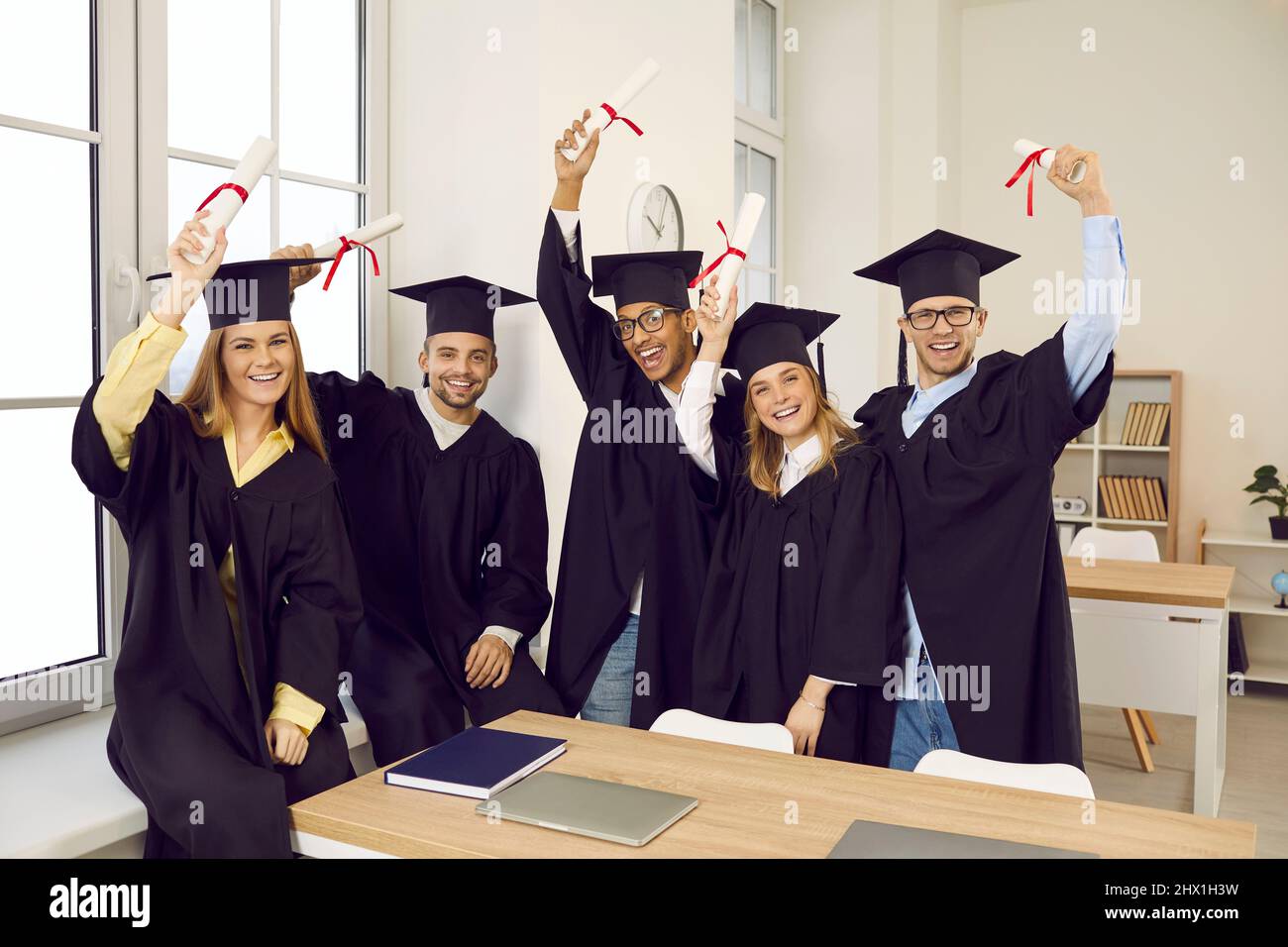Gruppo di studenti universitari o universitari felici e diversi che tengono in mano i diplomi e sorridenti Foto Stock